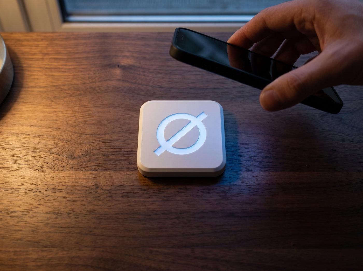A phone lowering onto a white Null Tag on a walnut desk, blue NFC bloom